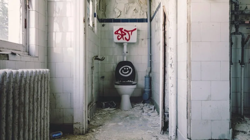 Verfallenes und verschmutztes Badezimmer mit Graffiti – Symbolbild für Streitigkeiten um Schönheitsreparaturen und Rückgabezustand im Rahmen einer Mietkautionsversicherung.