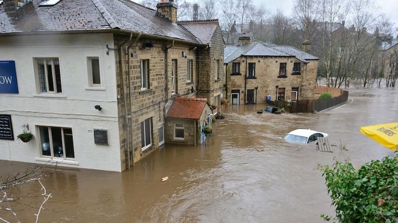 Überflutete Straße mit teils versunkenen Autos und Gebäuden nach Starkregen – Symbolbild für Elementarschäden bei Schäden durch Naturereignisse.
