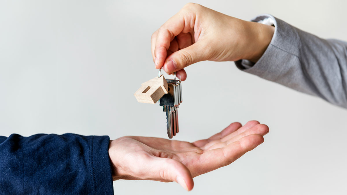 Symbolische Schlüsselübergabe zwischen zwei Personen mit einem Schlüsselbund samt Hausanhänger – typisches Motiv für Mietbeginn, Wohnungsübergabe und Absicherung durch eine Mietkautionsversicherung.