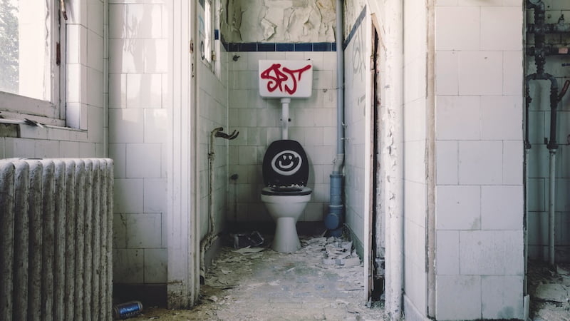 Verfallenes und verschmutztes Badezimmer mit Graffiti – Symbolbild für Streitigkeiten um Schönheitsreparaturen und Rückgabezustand im Rahmen einer Mietkautionsversicherung.