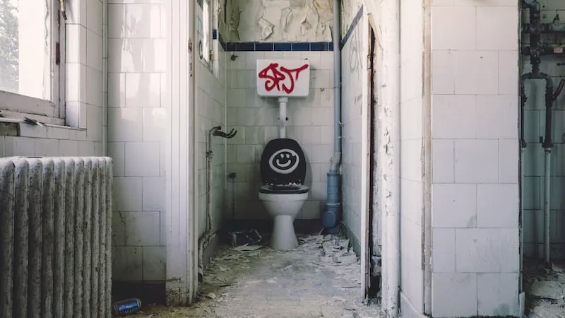 Verfallenes und verschmutztes Badezimmer mit Graffiti – Symbolbild für Streitigkeiten um Schönheitsreparaturen und Rückgabezustand im Rahmen einer Mietkautionsversicherung.