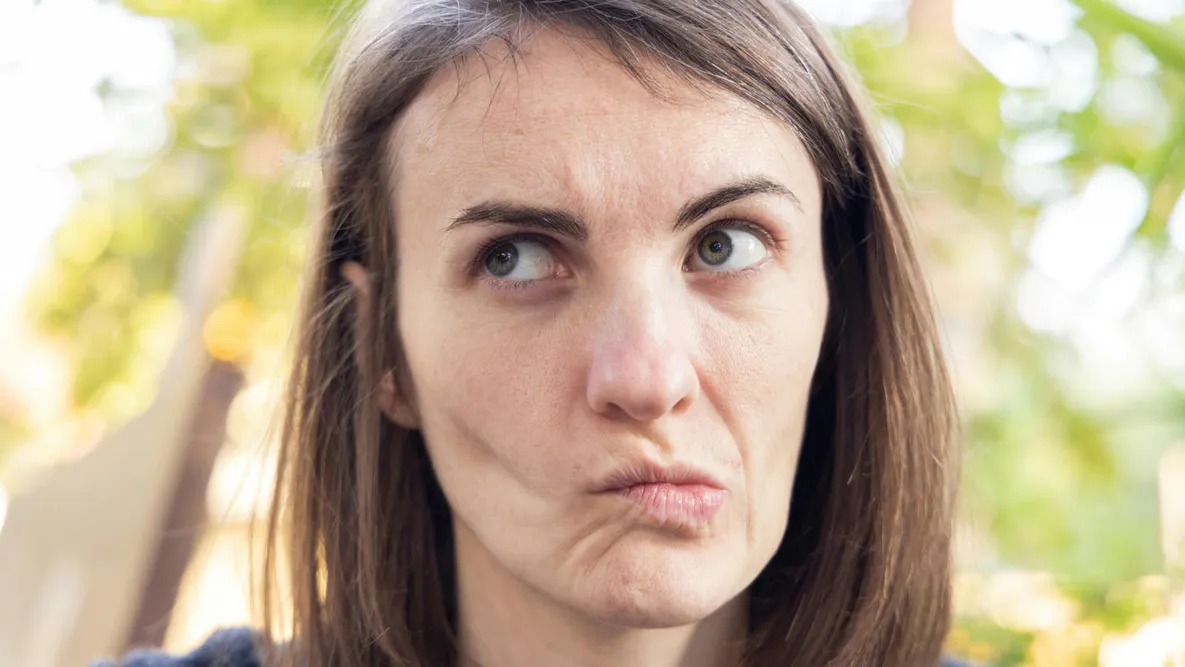 Nachdenkliche Frau mit skeptischem Gesichtsausdruck, Symbol für Unsicherheit und Fragen rund um die Mietkautionsversicherung.