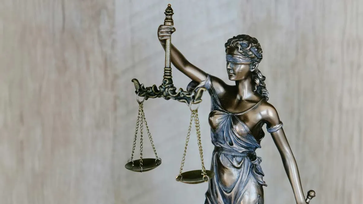 Bronzene Justitia-Statue mit verbundenen Augen und Waage – Symbol für Recht und Gerechtigkeit im Zusammenhang mit rechtlichen Aspekten der Mietkautionsversicherung.