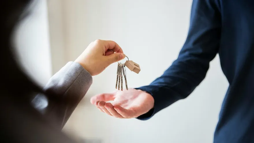 Übergabe von Wohnungsschlüsseln mit Schlüsselanhänger in Hausform – symbolische Darstellung für Miete, Einzug und Mietkautionsversicherung.